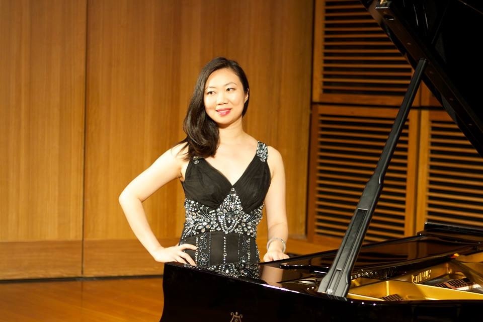 Pianist Ying Ho performing at the grand piano in concert dress